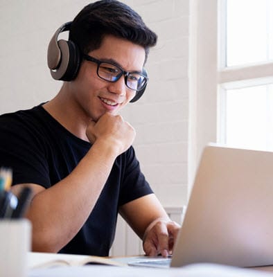 Student wearing headphones looking at a laptop.